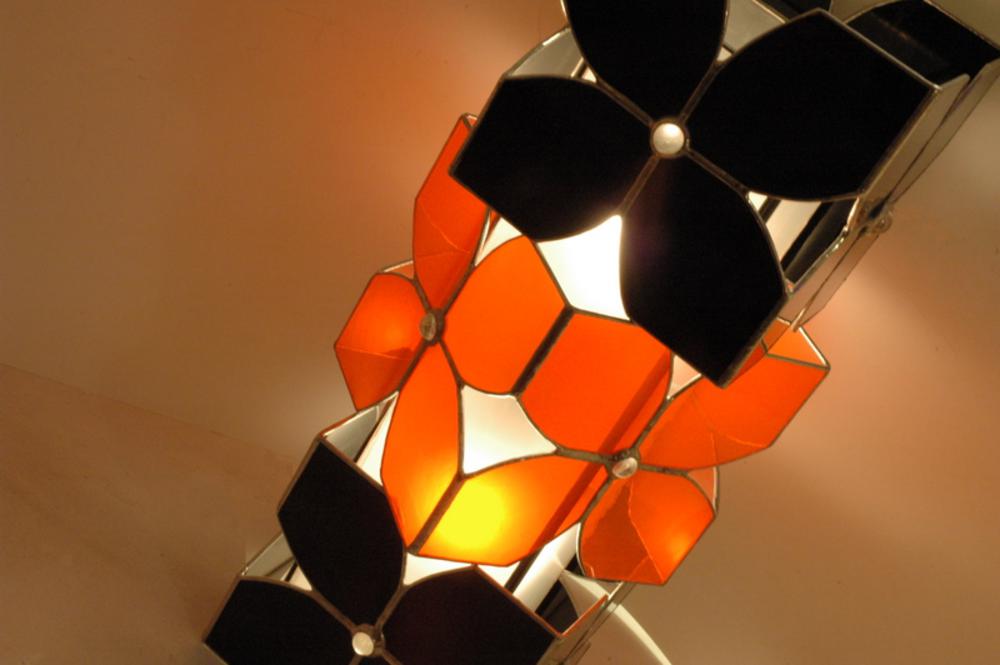 Vitraux oranges et noirs pour cette lampe à poser. Equipée de deux ampoules elle constitue une source de lumière intéressante en lampe d'appoint intégrée à la déco, sur un bureau ou une table de chevet.
